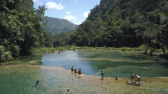AERIAL: People in Semuc Champey waterfalls in Guatemala alt