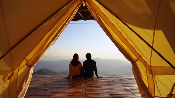 Young couple traveler looking beautiful landscape at sunset and camping on mountain