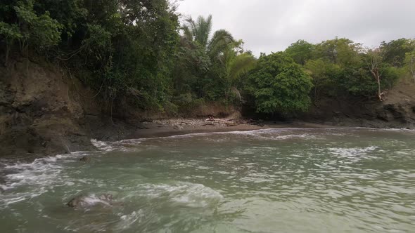 reverse drone flight from playa la vaca flying over the pacific ocean with a view of the waves break alt