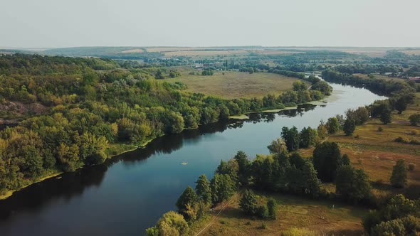 Aerial View. Flying over the beautiful sunny forest trees. Landscape panorama. alt