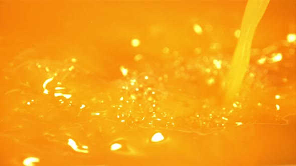 Super Slow Motion of the Stream of Orange Juice Pours with Splashes alt