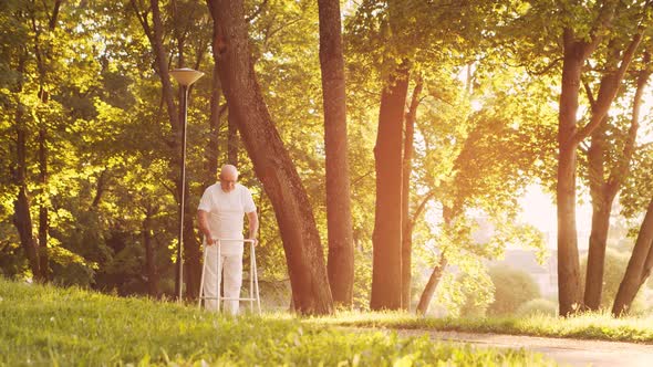 Disabled old man is walking with a walker. Handicapped patient in the park. alt