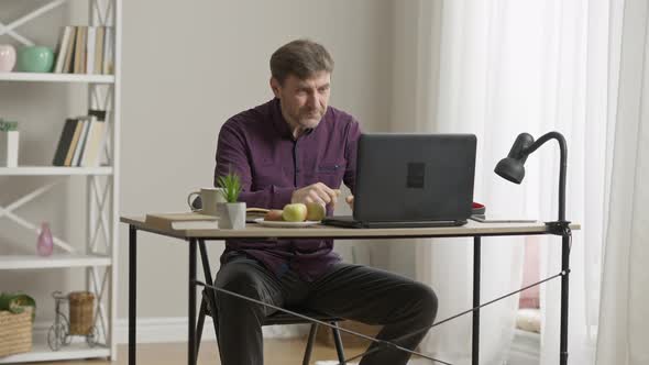 Wide Shot of Handsome Confident Middle Aged Man Adjusting Hair and Pointing at Laptop alt