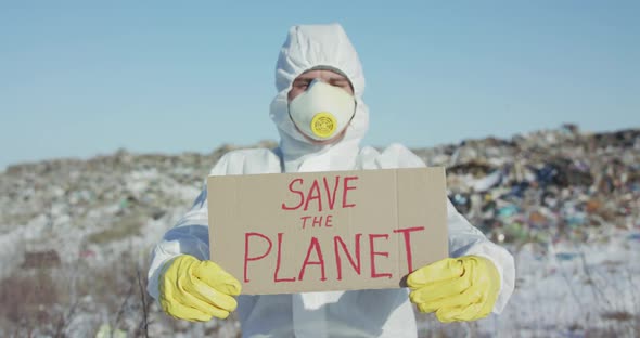 Portrait of Man Wore in Protective Suit Shows Protest Sign "Save the Planet" alt