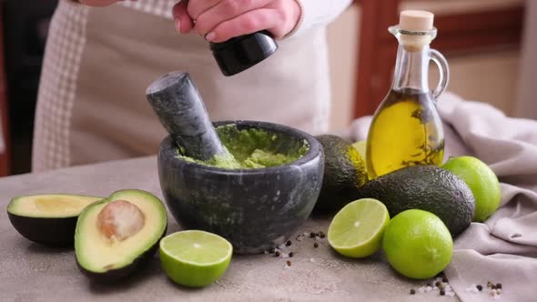 Making Guacamole Sauce Woman Adding Pepper and Spices to Mashed Avocado in a Marble Mortar with alt