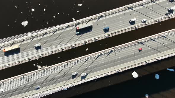 Aerial View of Trucks and Cars Driving on a Cable-stayed Bridge Over the River alt