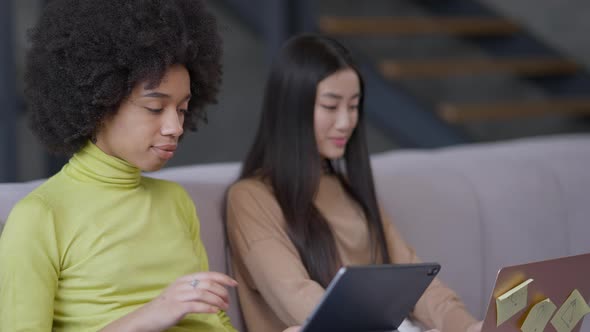Side Angle View of Smiling Charming African American Woman Messaging Online on Tablet with Blurred alt