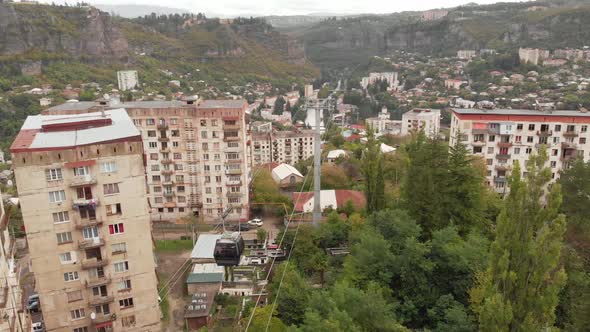 Cable Car Passing By Old Soviet Era Buildings in Chiatura Miners City in Georgia alt