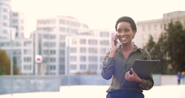 Young American Business Woman Walks Down Street in Classic Fashionable Dress, Carries Documents in alt