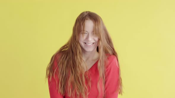 Energetic red-haired young woman happily dances and has an upbeat mood