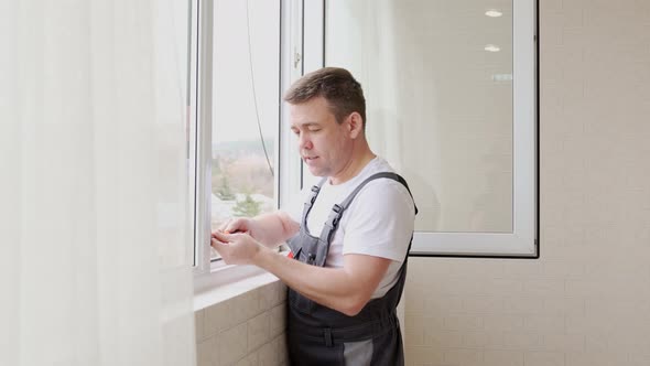 a Repairman Repairs Adjusts or Installs Metalplastic Windows in the Apartment alt