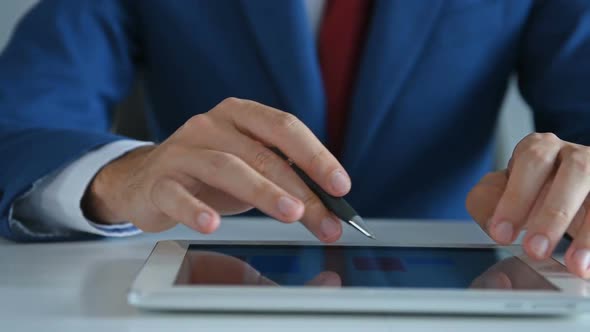 Businessman With Pen In Hand Using Digital Tablet with Business Report