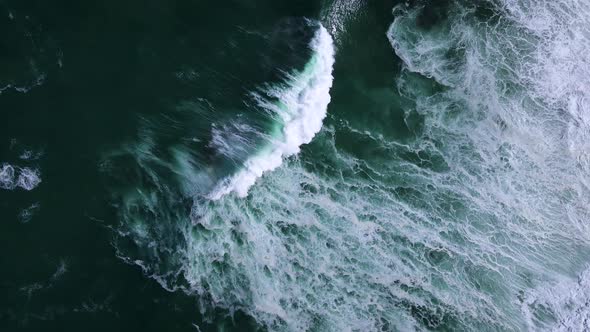 Moody ocean textures created by powerful crashing waves; drone descent alt