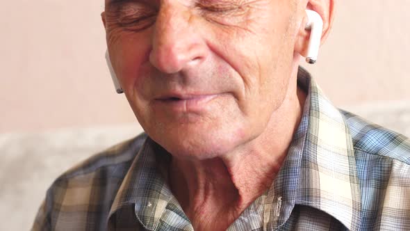 portrait of a cheerful Caucasian pensioner over 70 years old in airpods listening to music with his  alt