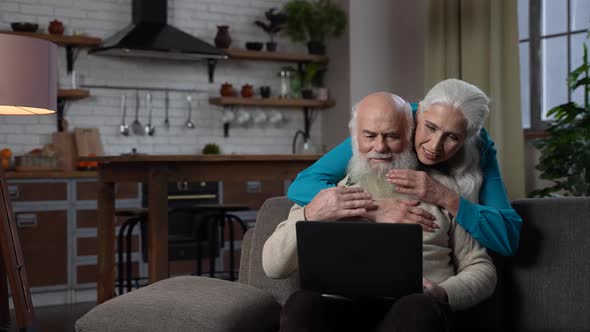 Loving Aged Couple Using Laptop for Video Call alt
