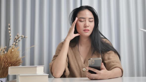 Asian girl is disappointed. She is checking cryptocurrency charts and stocks are falling