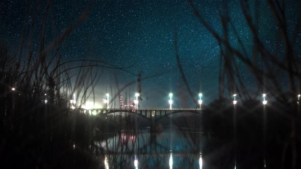 Night Timelapse Stars in City with Bridge and River