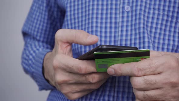 Closeup of Man Hands Holding Credit Card and Using Smartphone alt