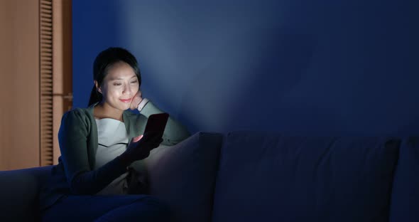Asian woman look at cellphone and sit on couch alt