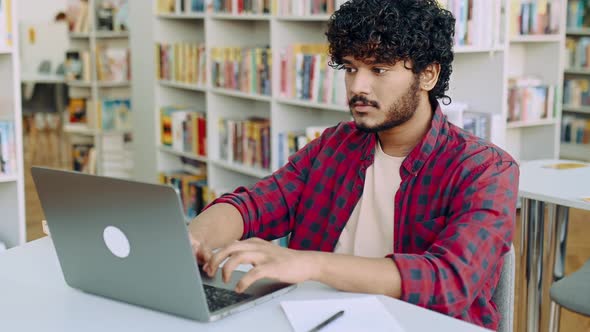 Clever Confident Positive Arabian or Indian Male Student Stylishly Dressed Sit at Table with Laptop alt