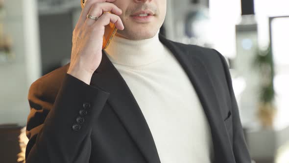 Confident Businessman In Suit Talking On Phone While Standing In Restaurant
