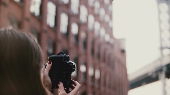 Back View Professional Female Photographer with Camera Takes Pictures of Brooklyn Bridge at Dumbo alt