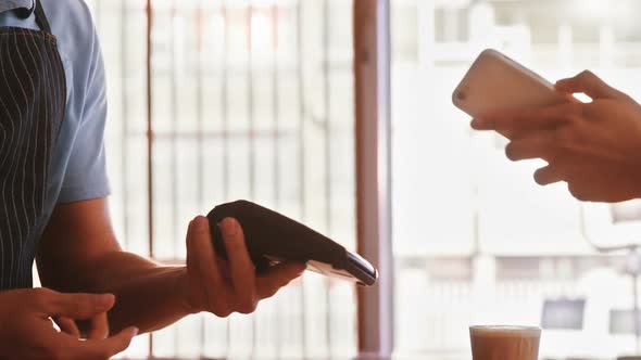 Woman Paying Bill With Smartphone alt