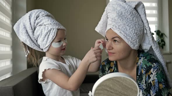 67 Year Old Girl Helps Her Mother Apply Cosmetic Patches Under Her Eyes alt