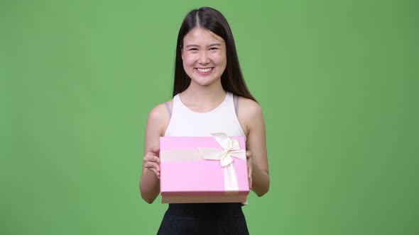 Young Beautiful Asian Businesswoman Thinking While Holding Gift Box