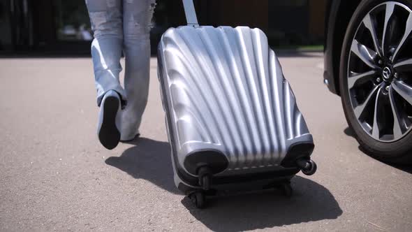 Legs of Woman Carrying Suitcase Walking From Car alt