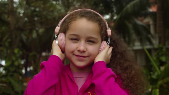 Footage Out of Focus Portrait of Cute Little Girl With Headphones Listening To Music alt