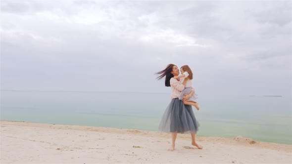 Cheerful and Carefree Mother Playing with Her Daughter on the Beach alt