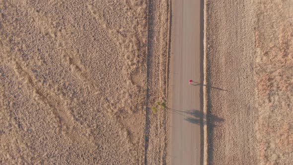 Birds eye view of a runner running on a gravel road during winter morning alt