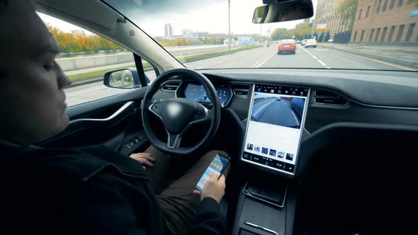 Man Sits in an Electric Car Going on Autopilot. Futuristic Automated Electric Car Self Driving alt