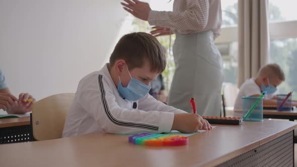 Multiracial Group of Kids Wearing Face Masks Working at Class Writing and Listening Explanations of alt
