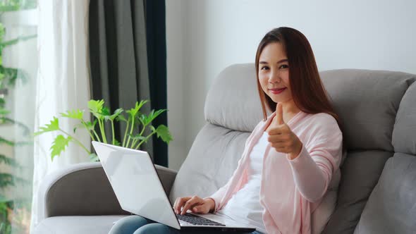 Young asian happy confident entrepreneur working with a laptop gesturing thumbs up