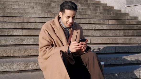 Positive Arabian man texting by phone alt