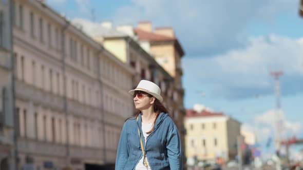Happy Brunette Woman Travels Around the City Woman in Hat Walking Through the City