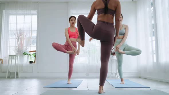 Asian female yoga teacher is teaching students in class basic exercise