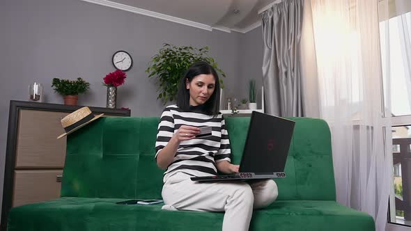 Woman at Home and Making Online Purchases Using Laptop and Personal Credit Card alt