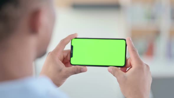 African Man Watching Smartphone with Green Chroma Key Screen alt