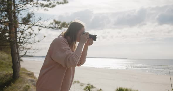 Young Woman Photographer Takes Pictures of the Sea Using Digital Camera