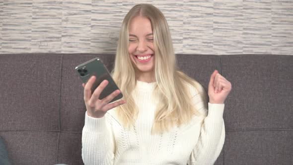 Exited smiling girl using smartphone, celebrating success, victory, achievement. alt