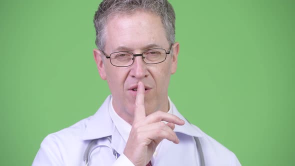 Portrait of Mature Man Doctor with Finger on Lips