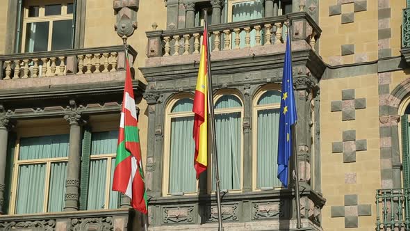 Flags of EU, Spain and Basque Country Waving on Government Building Facade alt