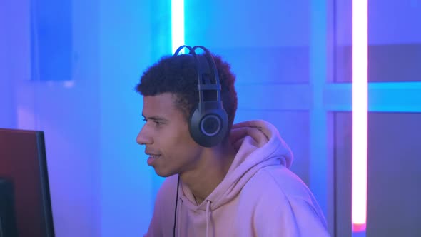 Close-up of Cheerful African Gamer in Headphones Playing Online Video Game alt