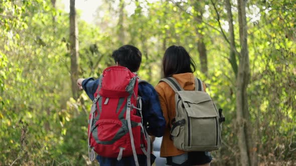 Young couple Asian tourists walking in the forest on sunny beautiful summer. alt