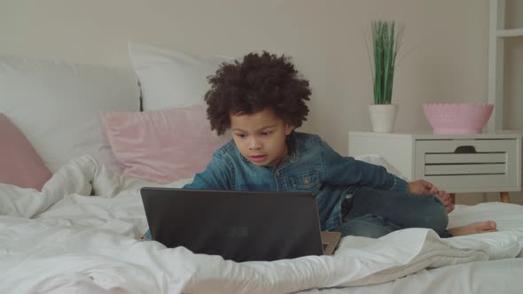 Multiethnic Boy Watching Video Online Using Laptop alt