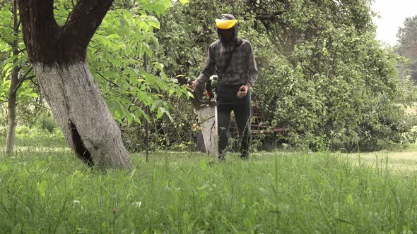 Worker with a gas mower in his hands, mowing grass in front of the house alt
