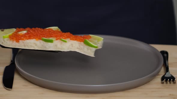 Sandwich with red caviar in shape of fish with lemon put on plate. Seafood alt